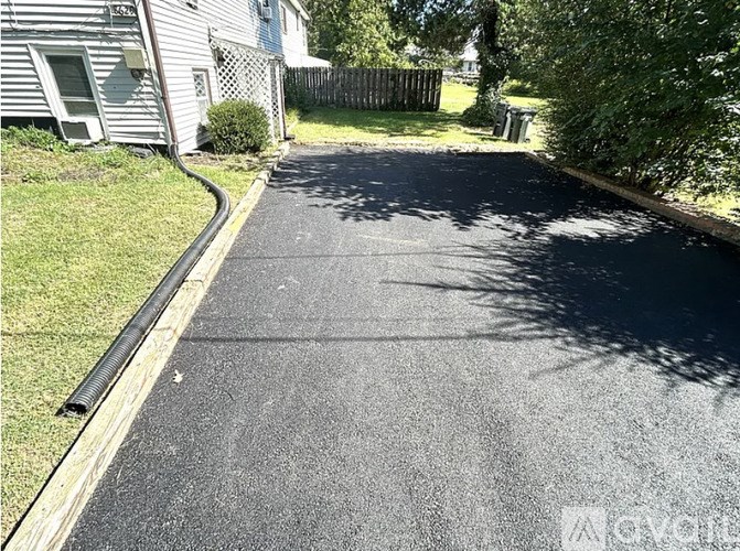 A driveway with a blacktop surface and a white border.