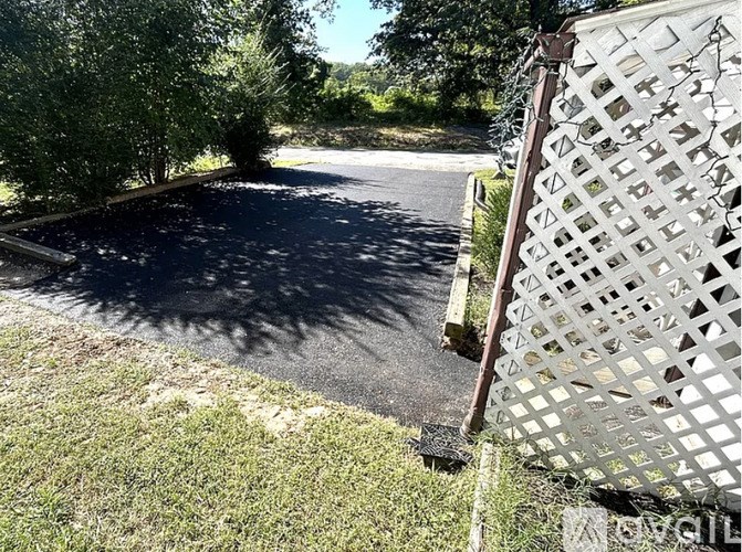 A white lattice fence borders a dark asphalt area.