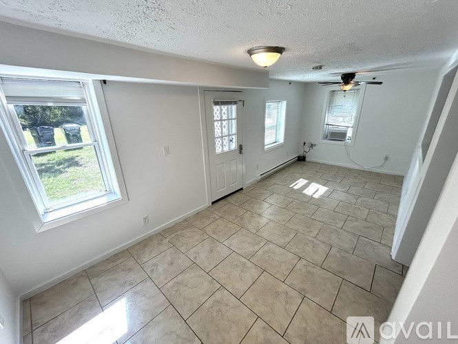 A room with tile flooring and a window overlooking a yard.
