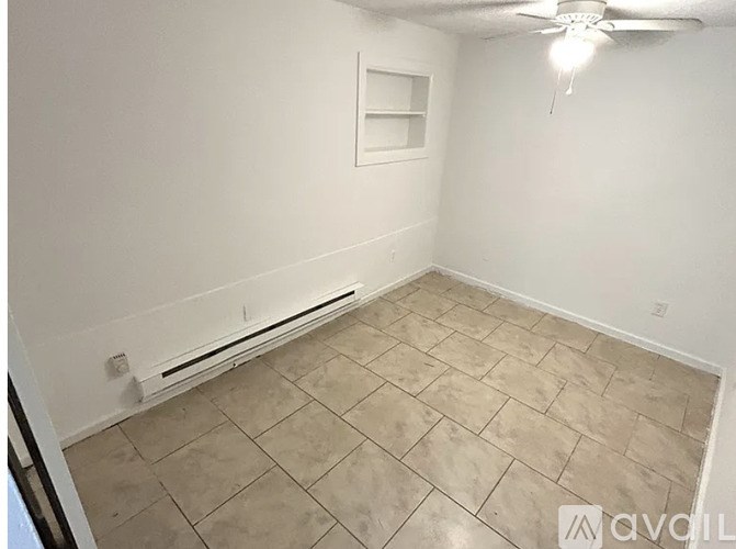 A room with a ceiling fan and a radiator on the wall.