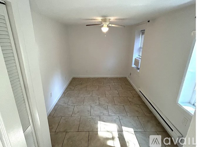 A room with tiled flooring and a window on the right side.
