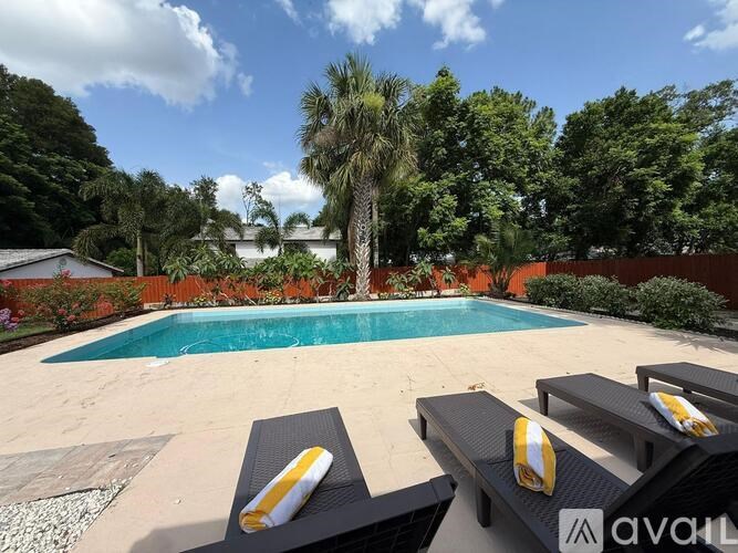 A pool surrounded by trees and lounge chairs.