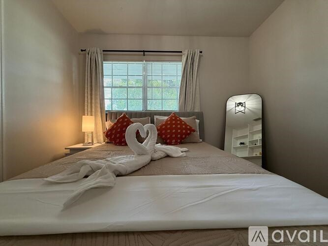 A bedroom with a bed, two lamps, a nightstand, and a window with curtains.