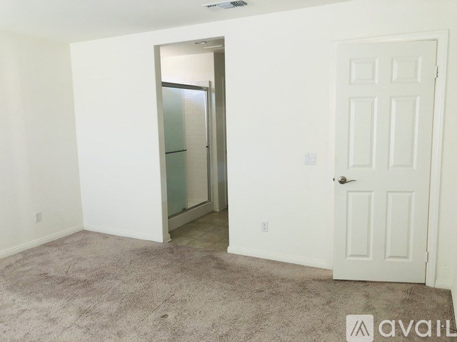 A room with a white door and a carpeted floor.
