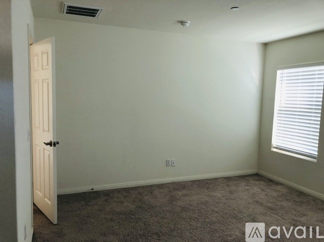 A room with a carpeted floor, a door, and a window with blinds.