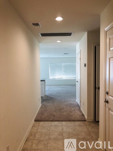 A hallway with a carpeted floor and a door on the right.