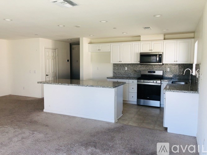 A kitchen with white cabinets and a granite countertop.