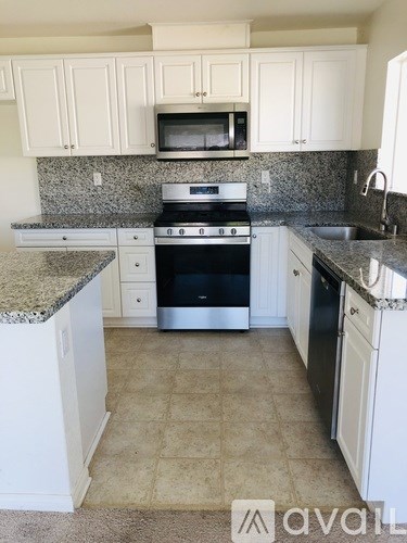 A kitchen with white cabinets and a granite countertop.