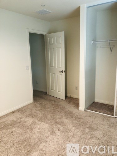 A room with a white door and a carpeted floor.