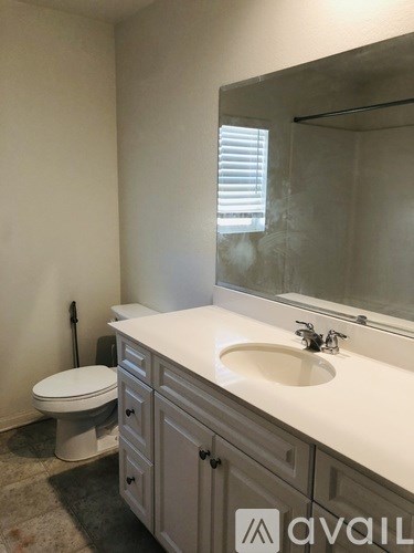 A bathroom with a toilet, sink, and mirror.