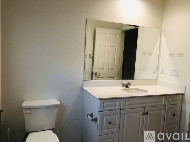 A bathroom with a toilet, sink, and mirror.