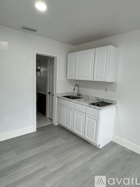 A kitchen with white cabinets and a marble countertop.