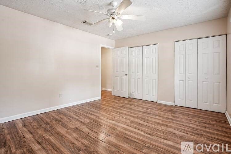 A room with a ceiling fan and wood flooring.