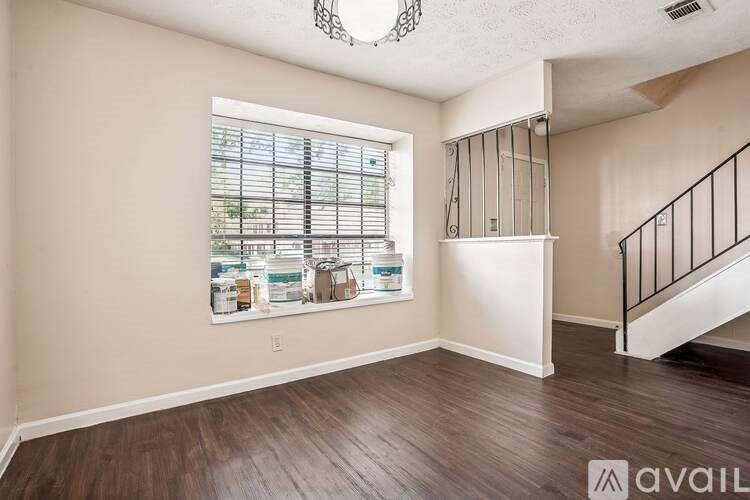 A room with a window showing a view of a kitchen with a sink and a fridge.