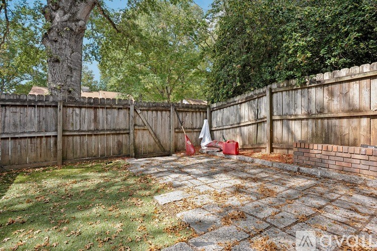 A backyard with a wooden fence and a tree.