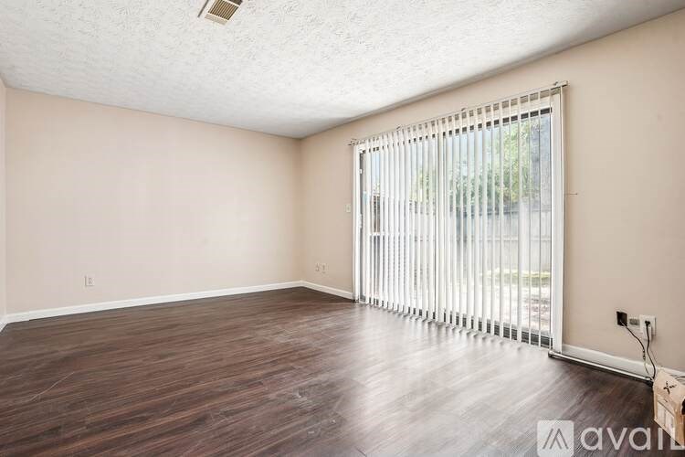A room with wooden flooring and a window with blinds.