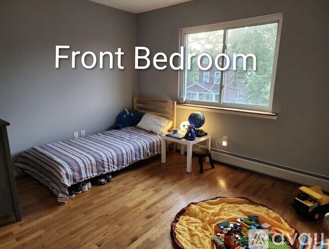 A bedroom with a bed, desk, and window.
