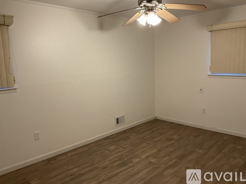 A room with a ceiling fan and wooden flooring.