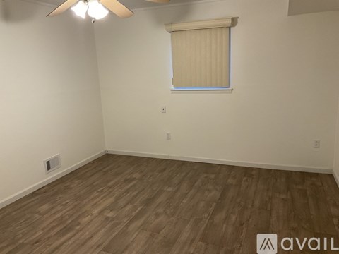 A room with wooden flooring and a window with blinds.