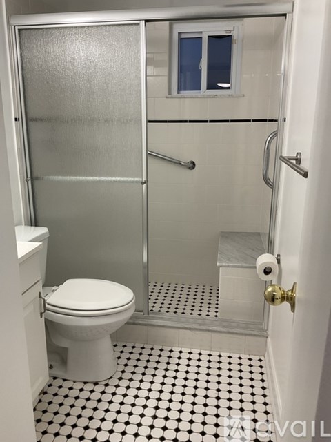 A white toilet in a small bathroom with a glass shower stall.