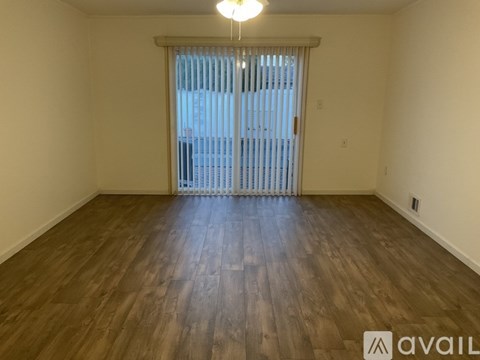 A room with wooden flooring and a window with blinds.
