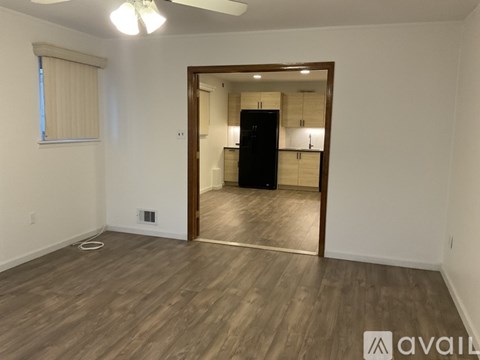 A room with wooden flooring and a doorway leading to another room.