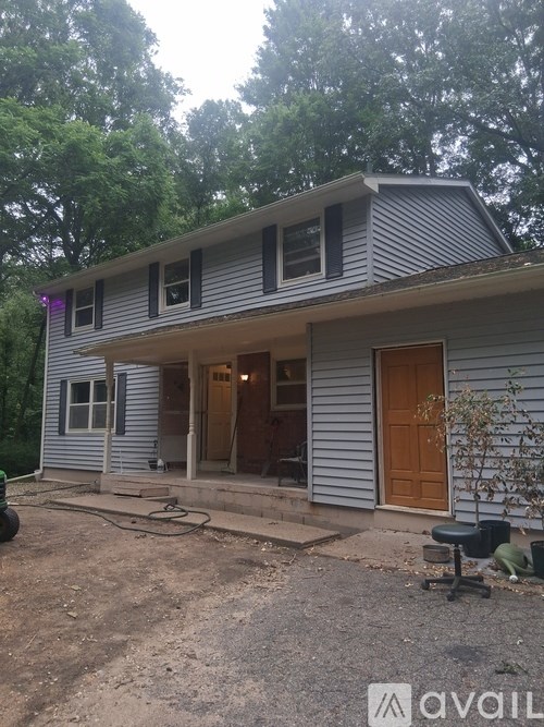 A house with a grey siding and a brown door is for sale.