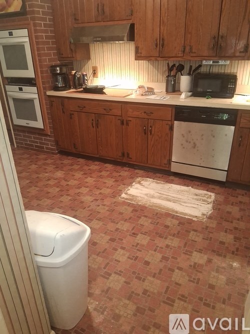 A kitchen with a white dishwasher and wooden cabinets.