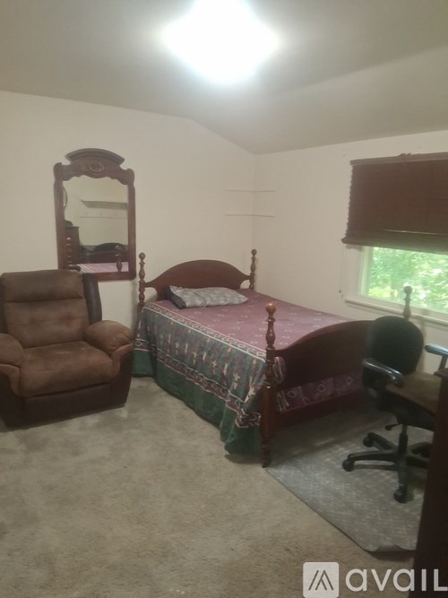 A bedroom with a bed, chair, and desk.