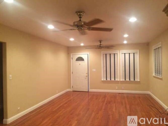 A room with a ceiling fan and recessed lighting.