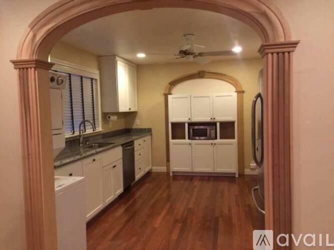 A kitchen with white cabinets and a wooden floor.