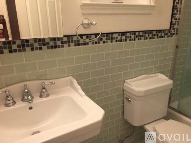 A white sink with chrome faucets and a white toilet in a bathroom.