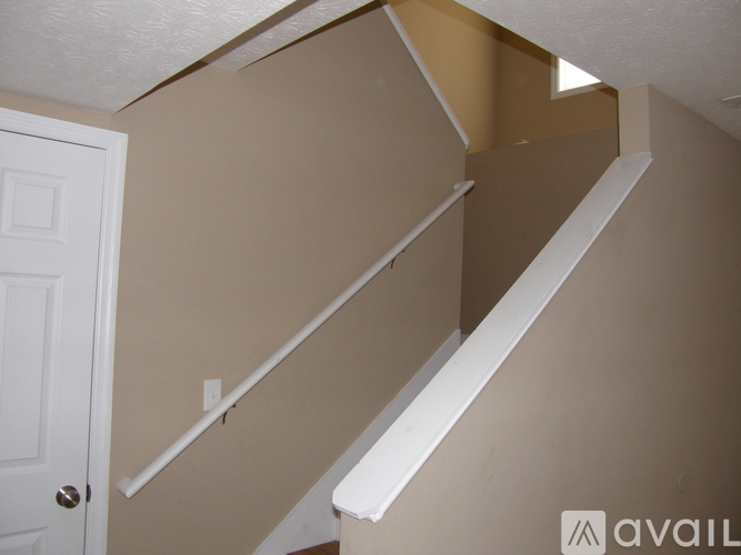 A white staircase with a white door on the left.