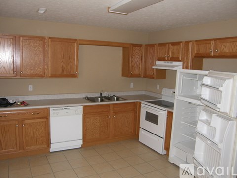 A kitchen with white appliances and wooden cabinets.