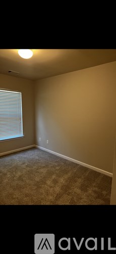 A room with a carpeted floor and a window with blinds.