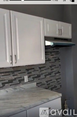 A kitchen with white cabinets and a stone backsplash.