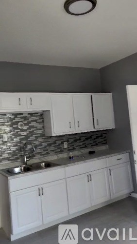 A kitchen with white cabinets and a stone backsplash.