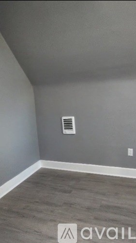 A room with a grey wall and a vent.
