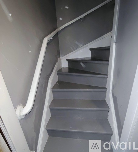 A staircase with a white handrail and grey steps.