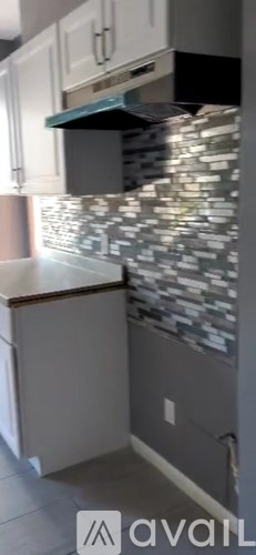 A kitchen with a tile backsplash and white cabinets.