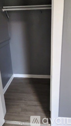 A white door is open to a room with a grey wall and wooden floor.