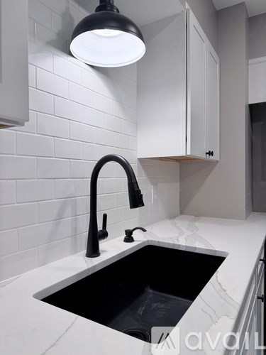 A modern kitchen with a black faucet and a white sink.