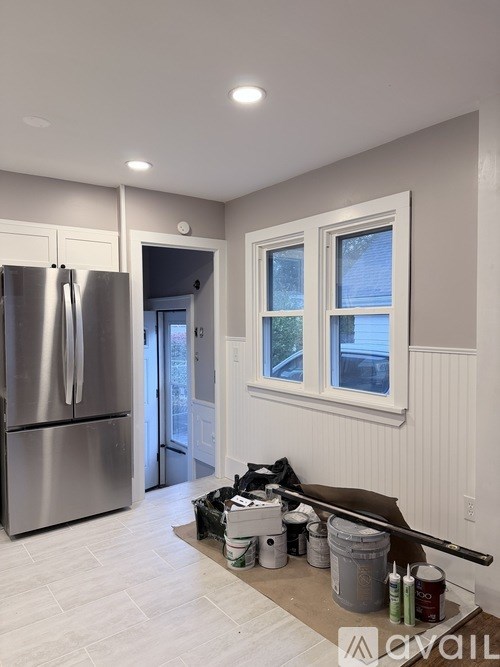 A kitchen with a refrigerator, a window, and painting supplies.