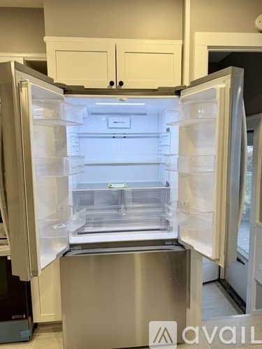 A white refrigerator with its door open and empty.
