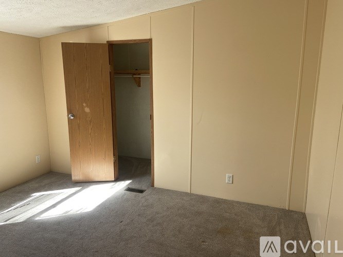 A room with a carpeted floor and a wooden door.