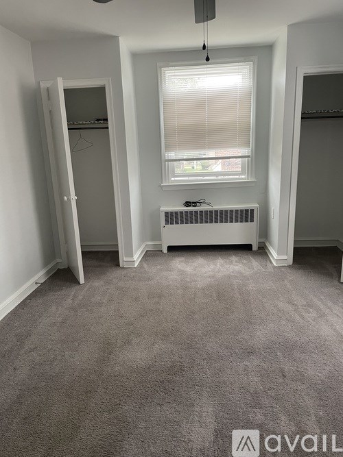 A carpeted room with a window and a radiator.