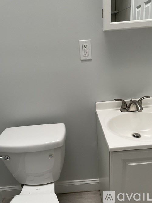 A white toilet sits next to a white sink in a bathroom.