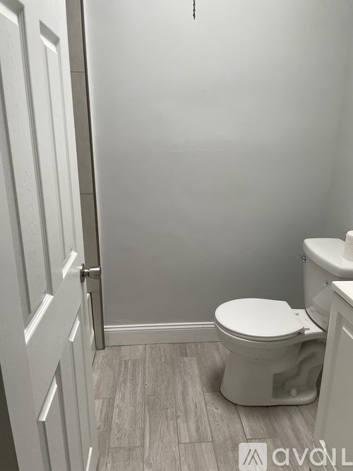 A white toilet in a bathroom with a wooden floor.