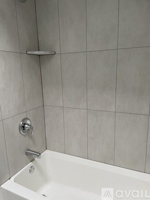 A white bathtub with a silver faucet and a silver bar on the wall.