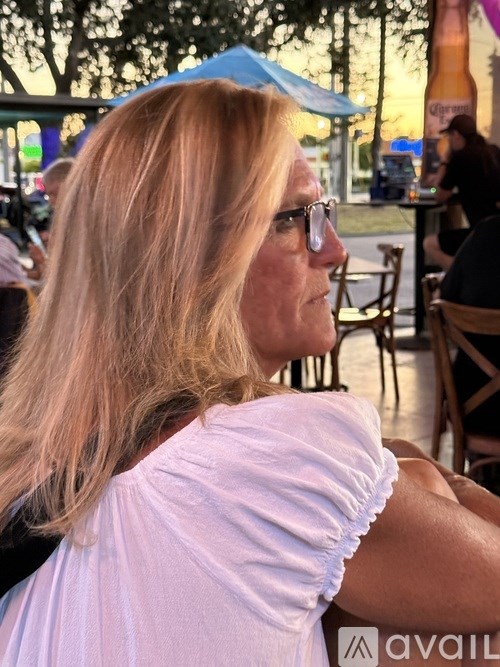 A woman with blonde hair is sitting outside at a table.